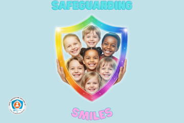  A diverse group of smiling children, framed within a large, brightly colored, rainbow-hued shield held by two hands at the bottom. The shield appears to shimmer with light. There are seven children visible within the shield, all looking directly at the viewer with happy expressions. The background is a soft, light blue.